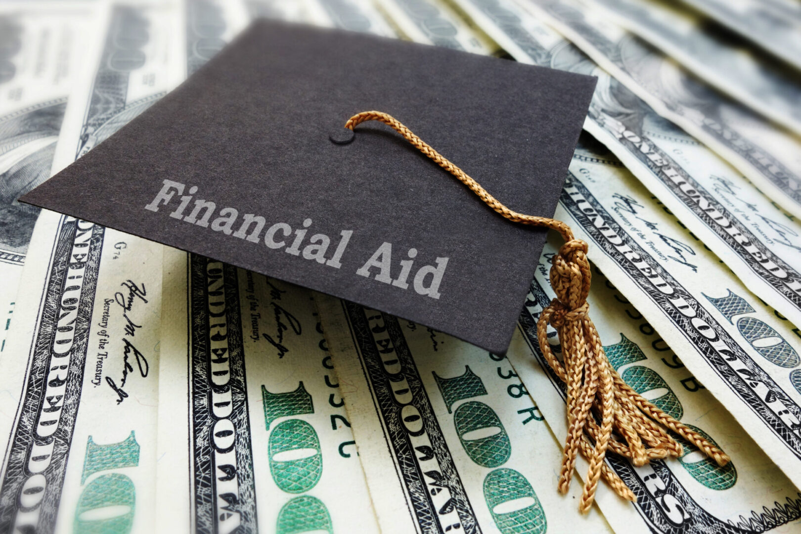 Mini Financial Aid graduation mortar board cap on money